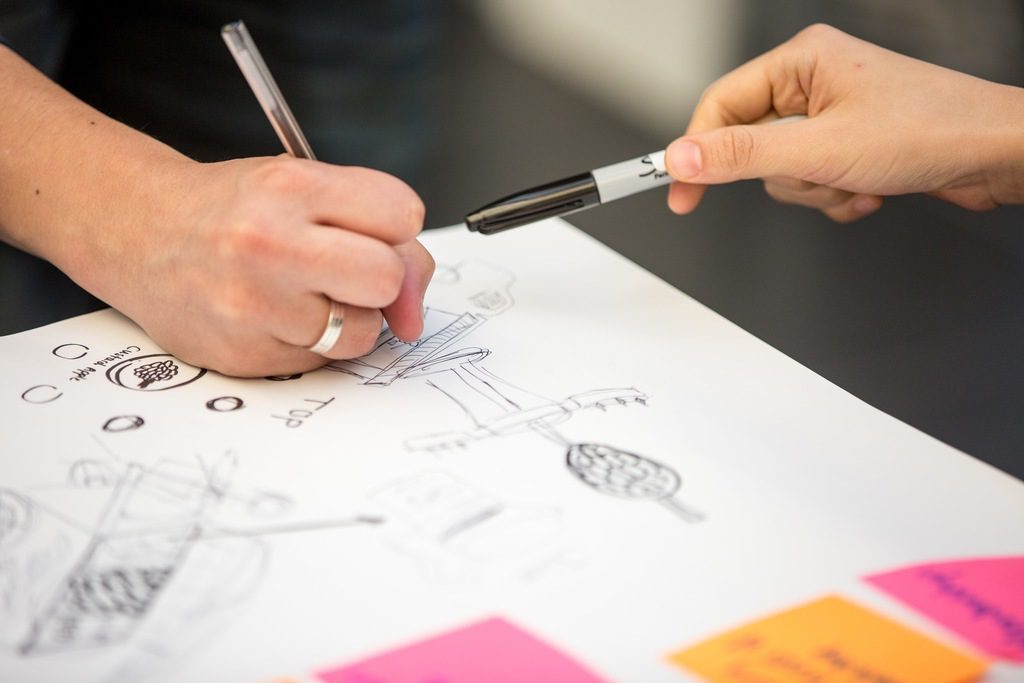 Mãos escrevendo sobre papéis indicando o passo a passo de como registrar uma patente