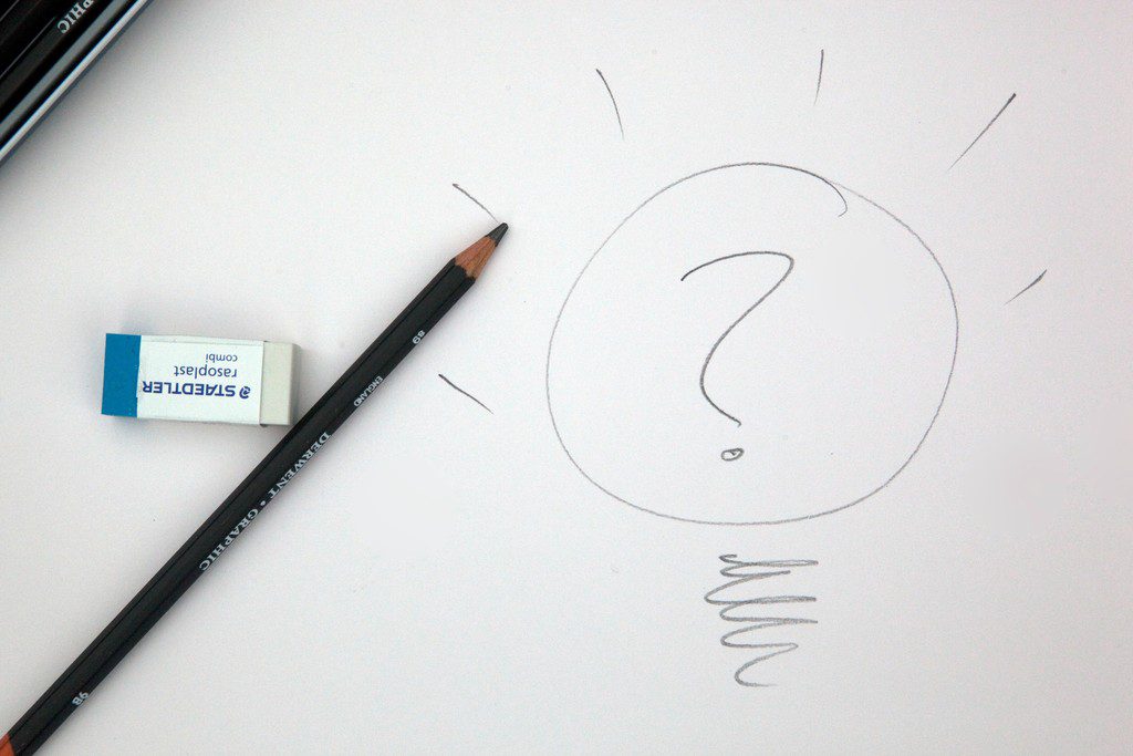 Borracha e lápis de escrever sobre uma folha de sulfite, na qual está desenhado um ponto de interrogação, simbolizando dúvidas sobre como registrar marca e sobre apresentação da marca