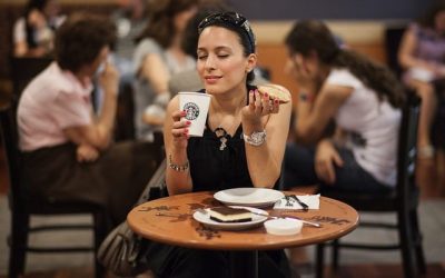 Foto de uma mulher bebendo café starbucks com cara de satisfação ilustrando uma marca de café fortalecida com o seu registro de marca.