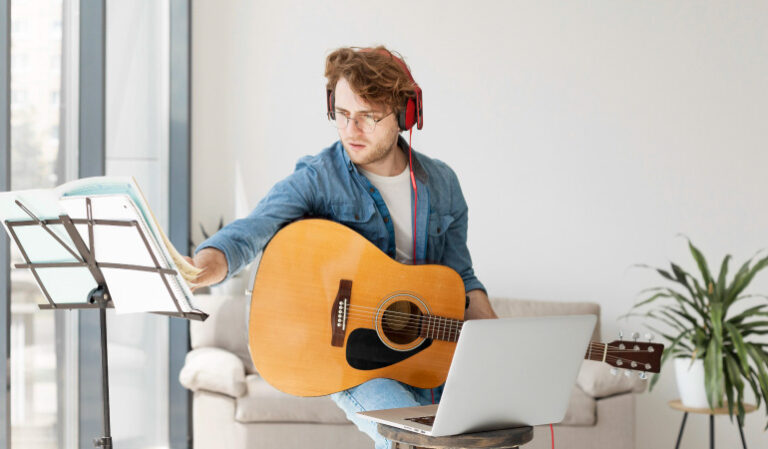 student-playing-guitar-wearing-headphones-medium-shot